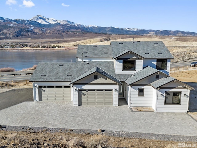 view of front of property with a water and mountain view and a garage