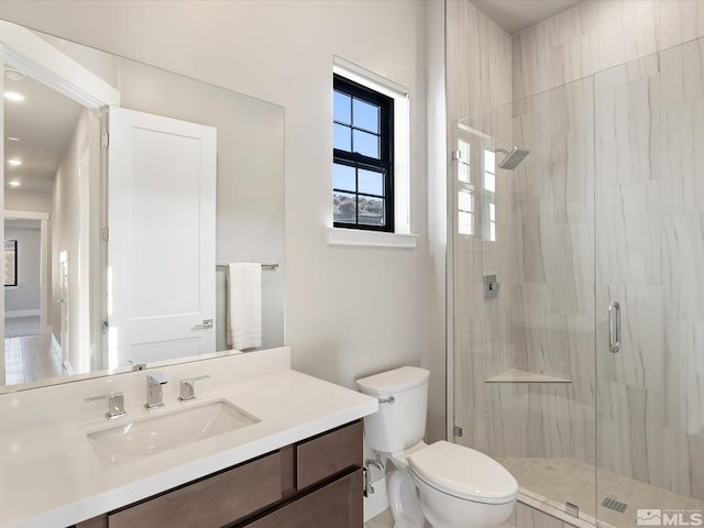 bathroom with toilet, a shower with door, and vanity