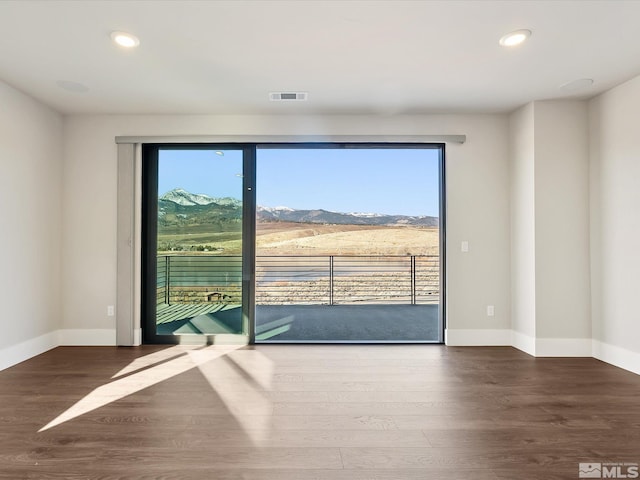 interior space with dark hardwood / wood-style floors, a wealth of natural light, and a mountain view