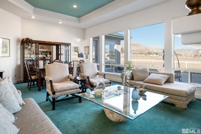 living room with carpet floors, a tray ceiling, crown molding, and a mountain view