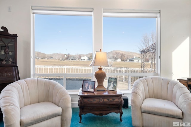 sitting room with carpet floors, a healthy amount of sunlight, and a mountain view