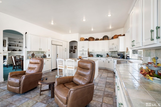 kitchen with tile counters, tasteful backsplash, white appliances, and white cabinets