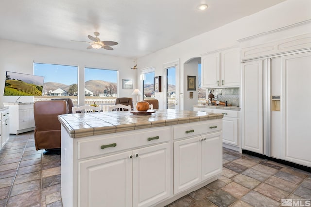 kitchen with white cabinetry, ceiling fan, tile countertops, and a mountain view