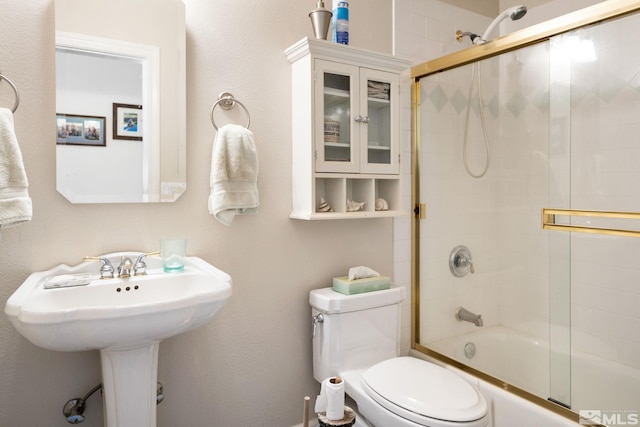 bathroom featuring toilet and bath / shower combo with glass door