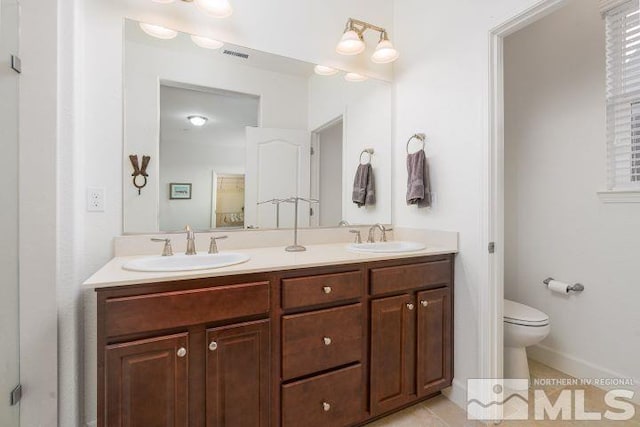 bathroom with toilet, vanity, and tile patterned floors