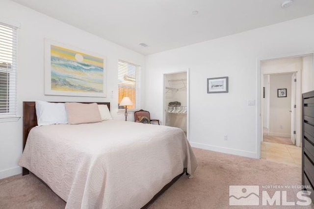 bedroom with a spacious closet, a closet, and light colored carpet