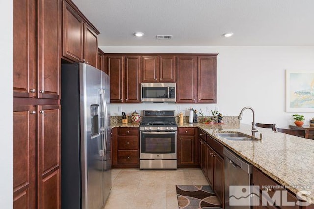 kitchen featuring light tile patterned flooring, light stone countertops, appliances with stainless steel finishes, and sink