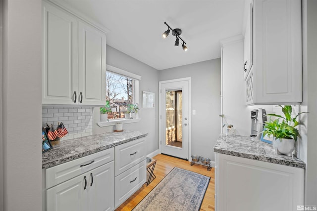 kitchen with white cabinetry, tasteful backsplash, and light stone countertops