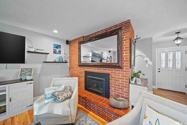 living room with a brick fireplace and hardwood / wood-style flooring