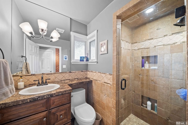 bathroom with toilet, a shower with shower door, tile walls, a chandelier, and vanity