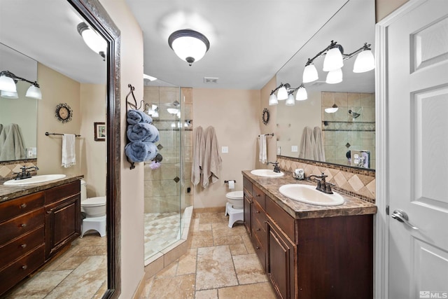 bathroom featuring a shower with shower door, toilet, vanity, and tasteful backsplash