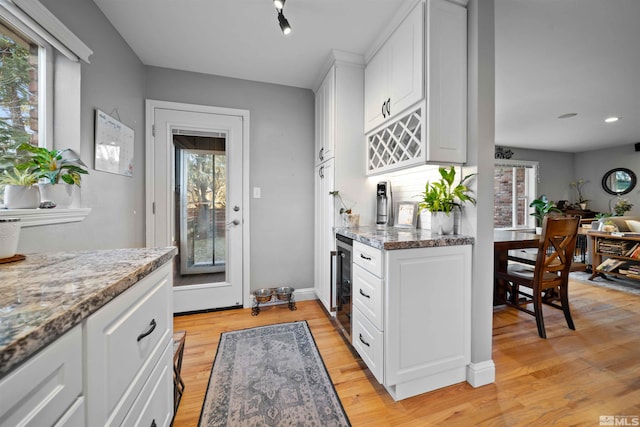 kitchen with white cabinets, light stone countertops, a wealth of natural light, and beverage cooler