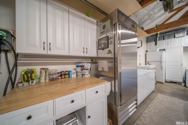 kitchen with stainless steel fridge, white fridge, and white cabinetry