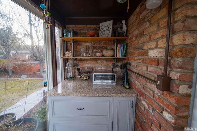 kitchen with brick wall and light stone counters