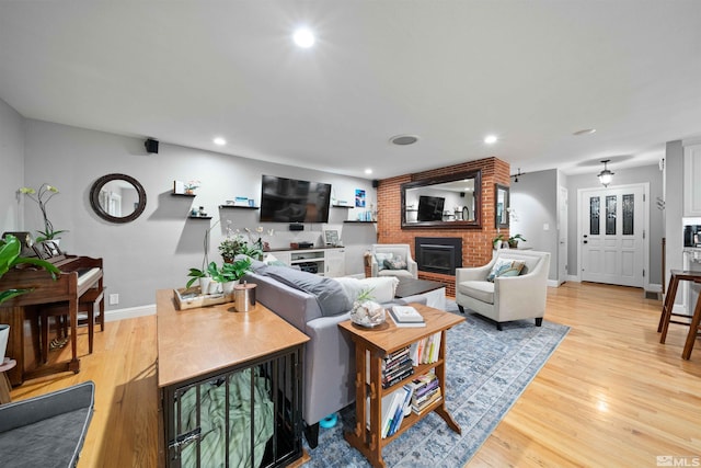 living room featuring a brick fireplace and light hardwood / wood-style flooring