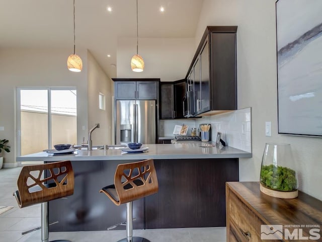 kitchen with decorative backsplash, a kitchen breakfast bar, appliances with stainless steel finishes, and kitchen peninsula