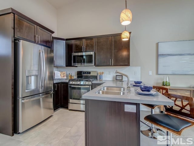 kitchen with stainless steel appliances, pendant lighting, dark brown cabinets, and sink