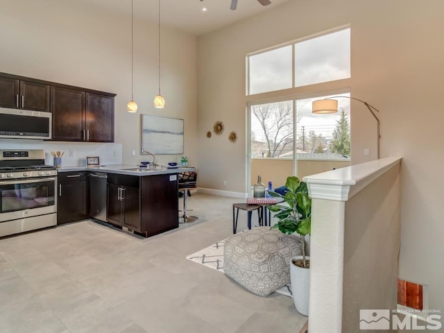 kitchen featuring kitchen peninsula, pendant lighting, stainless steel appliances, and a breakfast bar area