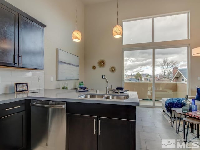 kitchen with pendant lighting, decorative backsplash, sink, kitchen peninsula, and stainless steel dishwasher