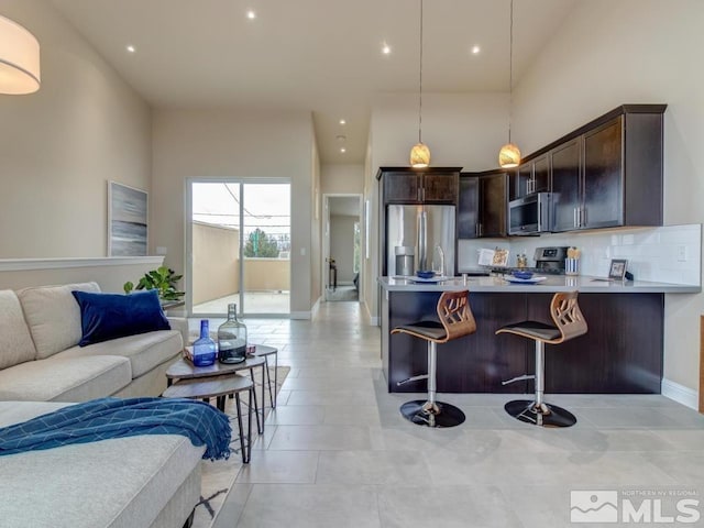 kitchen with hanging light fixtures, appliances with stainless steel finishes, dark brown cabinets, and a breakfast bar area