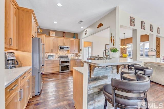 kitchen with dark wood-type flooring, stainless steel appliances, decorative backsplash, hanging light fixtures, and a notable chandelier