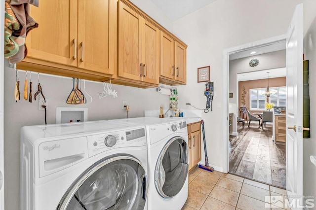 clothes washing area featuring light tile patterned flooring, independent washer and dryer, a chandelier, and cabinets