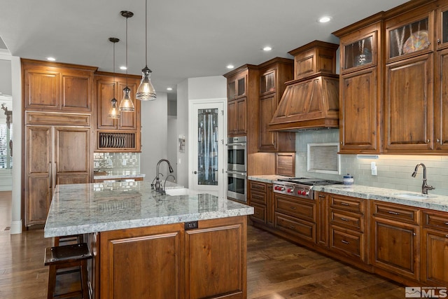 kitchen featuring a kitchen island with sink, appliances with stainless steel finishes, sink, and pendant lighting