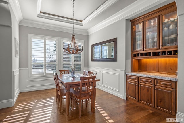 dining room with dark wood-type flooring, crown molding, a tray ceiling, and a notable chandelier