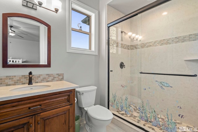 bathroom with toilet, vanity, ceiling fan, backsplash, and a shower with door