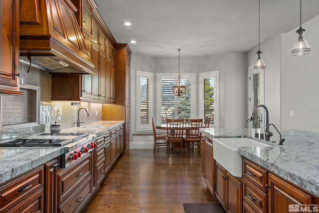 kitchen with pendant lighting, light stone counters, and sink