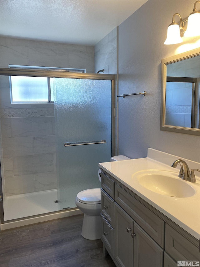 bathroom with hardwood / wood-style flooring, toilet, a shower with door, and vanity