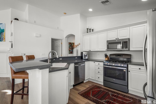 kitchen with a kitchen breakfast bar, stainless steel appliances, white cabinets, and kitchen peninsula