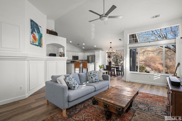 living room with high vaulted ceiling, wood-type flooring, and ceiling fan with notable chandelier