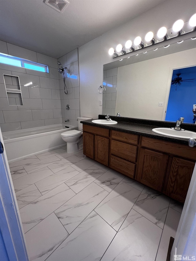 full bathroom with tiled shower / bath combo, vanity, and toilet