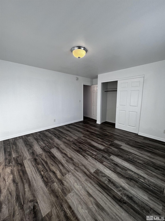 unfurnished bedroom featuring dark hardwood / wood-style floors and a closet