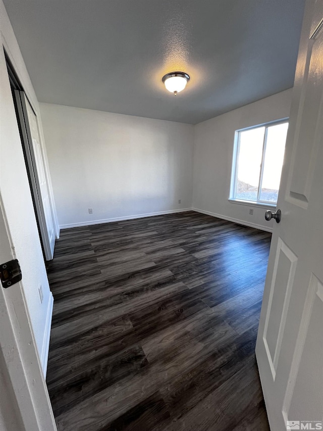 spare room with a textured ceiling and dark hardwood / wood-style floors