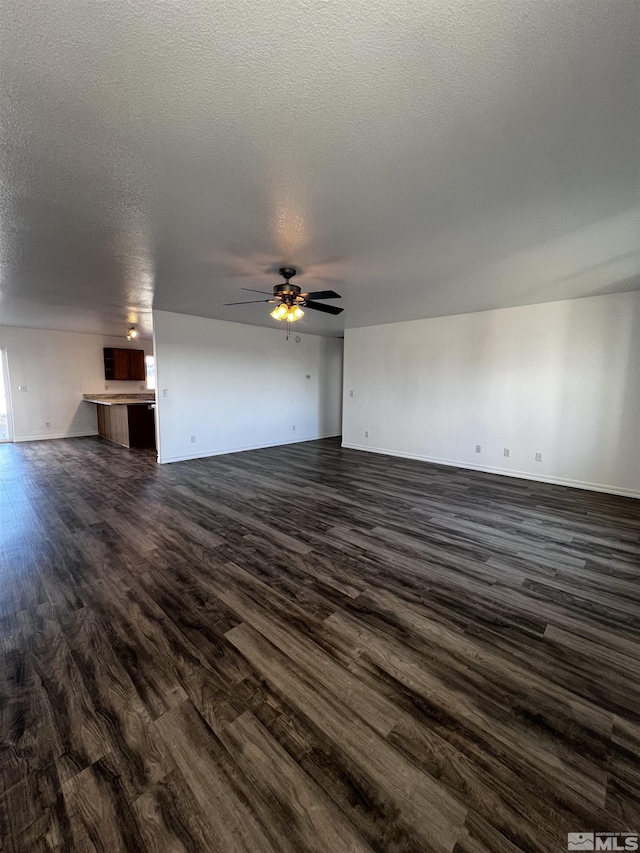 unfurnished living room featuring ceiling fan, a textured ceiling, and dark hardwood / wood-style floors