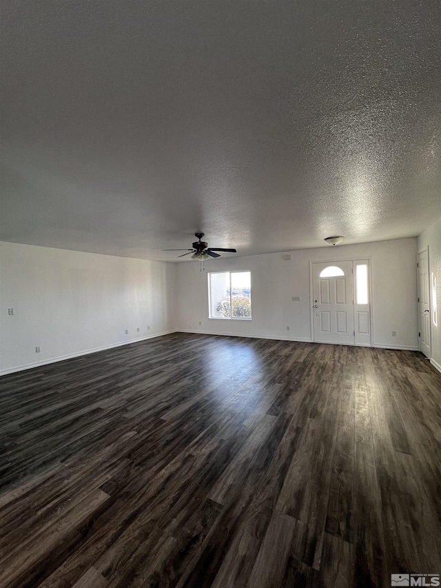 unfurnished living room with ceiling fan, dark wood-type flooring, and a textured ceiling