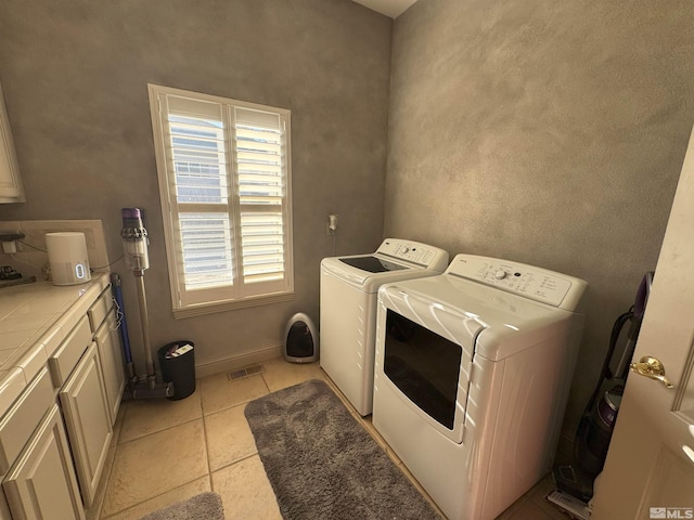 laundry area with washer and dryer, cabinets, and light tile patterned flooring