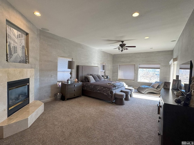 bedroom featuring ceiling fan, a tile fireplace, and carpet floors