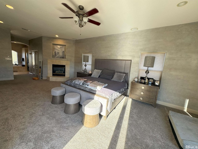 bedroom featuring ceiling fan, carpet, and a tile fireplace