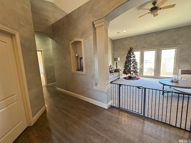 hallway with dark wood-type flooring, lofted ceiling, and ornate columns