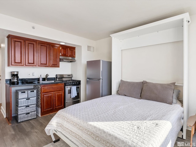 bedroom with dark hardwood / wood-style flooring, stainless steel fridge, and sink