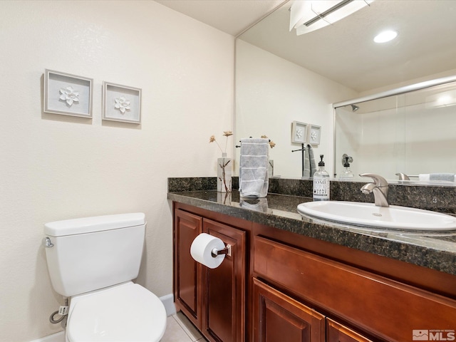 bathroom with a shower with shower door, tile patterned floors, vanity, and toilet