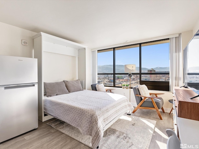 bedroom featuring light hardwood / wood-style floors and white fridge