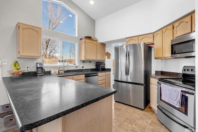 kitchen featuring kitchen peninsula, sink, a high ceiling, light brown cabinets, and stainless steel appliances