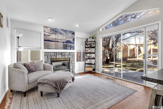 living room with lofted ceiling, a fireplace, and hardwood / wood-style floors