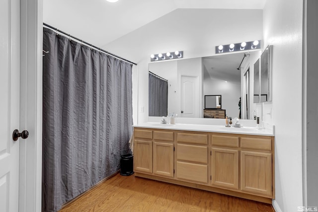 bathroom featuring hardwood / wood-style floors, vanity, and vaulted ceiling