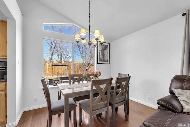 dining room featuring hardwood / wood-style floors, lofted ceiling, and a notable chandelier