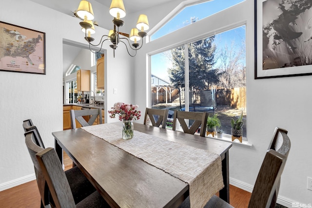 dining room with vaulted ceiling, an inviting chandelier, and hardwood / wood-style floors